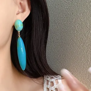 Primer plano de pendientes de gota de acrílico turquesa de estilo vintage en la oreja