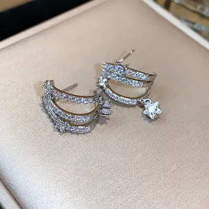 Dettaglio di eleganti orecchini a lobo in argento con zirconi e ciondolo a stella.