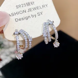 Primo piano di eleganti orecchini a lobo in argento con zirconi e ciondoli a stella.