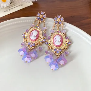 Close-up detail of vintage style cameo earrings with purple floral tassels and gold finish