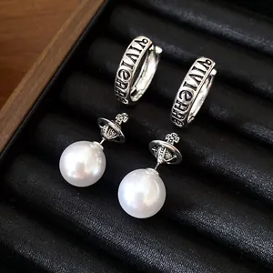 Close-up of Vivienne Westwood style silver hoop and pearl orb drop earrings in black tray