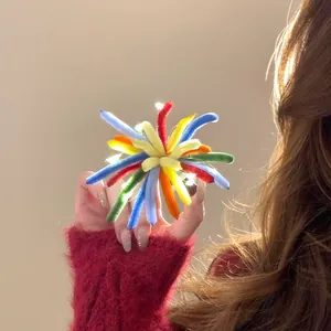 Close-up detail of a vibrant colorful flocked firework hair clip held by a model