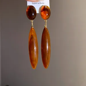 Vista detallada de pendientes de gota de acrílico ámbar vintage con eslabones dorados