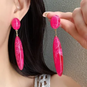 Vista detallada de pendientes de gota en acrílico rosa con una textura de mármol única