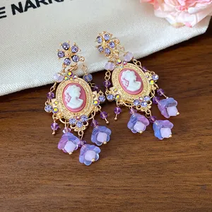 Close-up of vintage cameo earrings with purple crystals and floral resin tassels