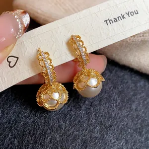 Close-up of elegant gold plated lace earrings featuring white pearls and micro-pave zircons