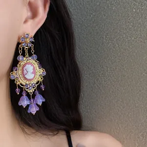 Detailed view of vintage court style purple crystal earrings with floral cameo on model ear