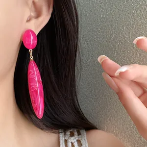 Detalle de pendientes colgantes de acrílico rosa intenso con textura marmoleada