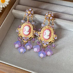 Close-up of vintage cameo earrings featuring purple crystal flowers and delicate petal drops
