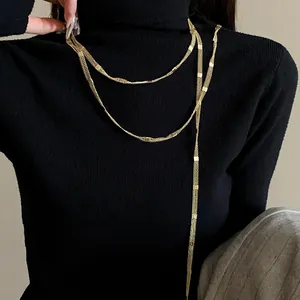 Close-up of minimalist gold long chain necklace worn over a black turtleneck sweater