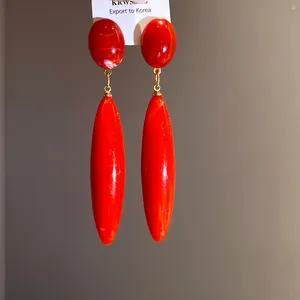 Primer plano detallado de pendientes largos vintage de acrílico de color rojo vivo