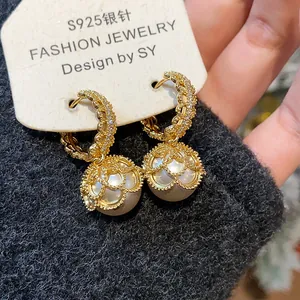 Close-up detail of gold plated lace pearl earrings with zircon accents on display card