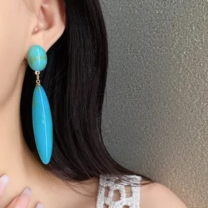 Elegante primer plano de pendientes colgantes de acrílico turquesa en una modelo