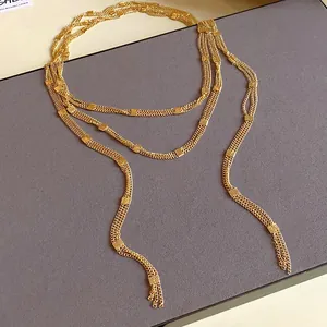 Detailed close-up of an elegant multi-layered gold chain necklace with square metallic accents