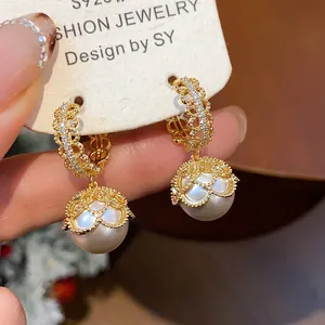 Detailed close-up of gold plated lace pearl earrings with sparkling zircon accents