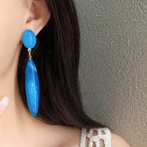 Primer plano detallado de elegantes pendientes largos de gota en acrílico azul para mujer