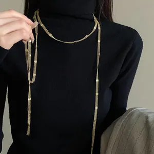 Detail of a minimalist gold multi-layer long chain necklace on a black sweater