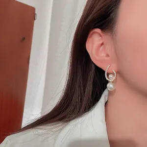 Close-up showing the detail of a twisted crystal and pearl earring worn on the ear.