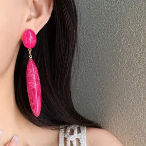 Primer plano de los pendientes colgantes de acrílico jaspeado rosa usados por modelo