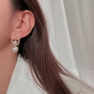 Close-up of elegant twisted silver earrings with rhinestones and pearls on ear