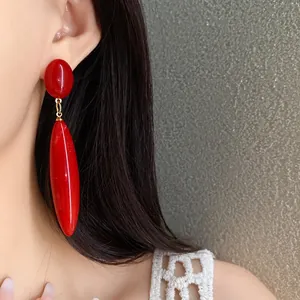 Primer plano detallado de pendientes de gota en acrílico rojo con un estilo vintage