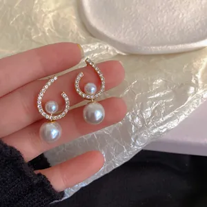 Close-up of elegant twisted silver needle earrings with pavé diamonds and double pearls