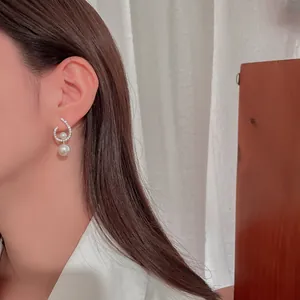 Close-up of elegant silver twisted earrings with sparkling rhinestones and white pearls