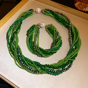 Detailed view of green multi-strand crystal bead necklace and bracelet set on a tray.