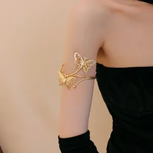 Detail shot of an elegant gold butterfly arm cuff worn by a model in a black dress