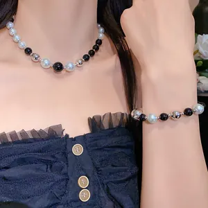 Close-up of fashion necklace and bracelet set with black, white, and silver beads on model