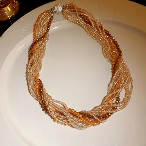 Close-up of twisted multi-strand crystal beads in amber and champagne tones on white.
