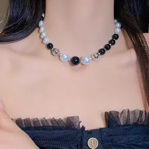 Close-up detail of a contrasting color irregular pearl necklace on a model's neck