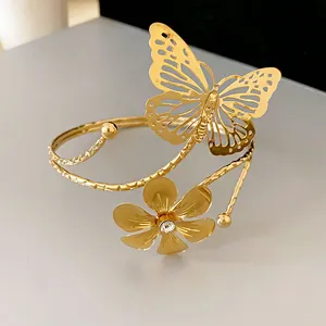 Detailed view of a gold open bangle featuring a hollow butterfly and a sparkling flower.