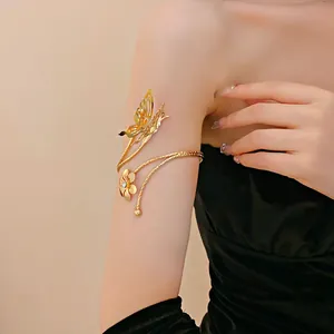 Detail of elegant gold butterfly and flower arm cuff bracelet worn on the upper arm