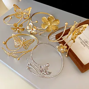 Close-up of elegant gold and silver open bracelets with floral and butterfly designs