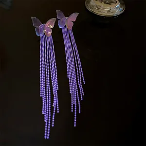 Detailed close-up of elegant purple butterfly stud earrings with long beaded tassels