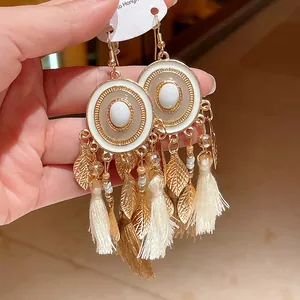 Vista dettagliata di orecchini boho rotondi con foglie dorate e nappe eleganti
