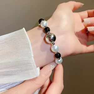 Close-up of chic black and white pearl beaded bracelet with silver orb on wrist