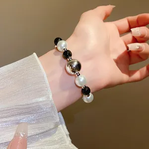 Close-up of minimalist beaded bracelet with black and white pearls and silver orb