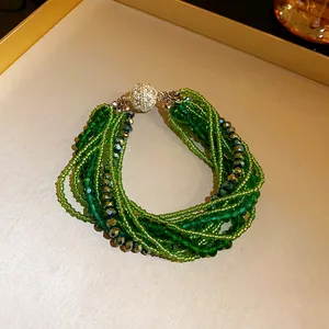 Close-up of bohemian multi-layer green crystal bead bracelet with pavé clasp