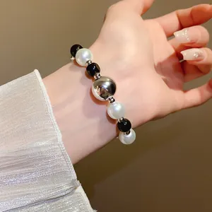 Close-up of an elegant black and white pearl bracelet with a silver metallic centerpiece.