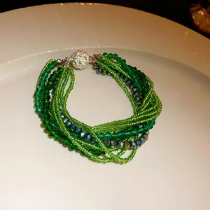 Close-up of bohemian multi-layer green crystal beaded bracelet with rhinestone clasp