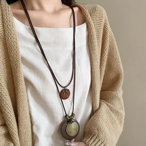 Detailaufnahme einer langen Halskette im Ethno-Stil mit Holzanhängern und Metallspirale