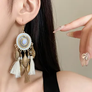 Dettaglio ravvicinato di orecchini boho con foglie e nappe sull'orecchio della modella