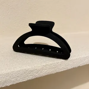 Vista laterale di una pinza per capelli nera opaca minimalista a forma di mezzaluna