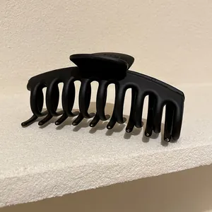 Dettaglio macro della molletta per capelli nera opaca con denti a presa forte e sicura.