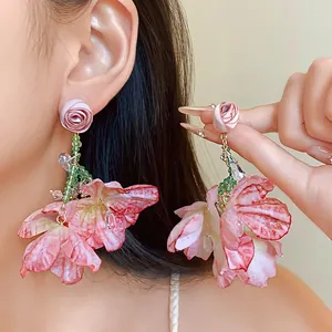 Close-up detail of sweet pink fabric rose and mesh flower earrings with crystal tassels