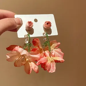 Close-up detail of romantic floral mesh earrings featuring crystal tassels and green beads