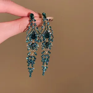 Gros plan sur des boucles d'oreilles pendantes à pompons zircon vert