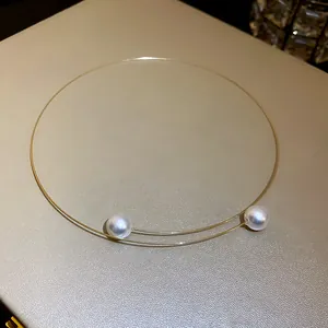 Detailed view of a minimalist double-strand gold wire choker with two white pearls